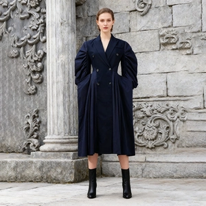 Detail view of navy double-breasted coat dress with statement puff sleeves and pleated hem