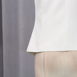 Close-up of white twill vest fabric showing clean side seams and refined stitching details