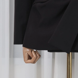 Close-up of fine stitching and fabric texture on a black blazer cuff and hemline