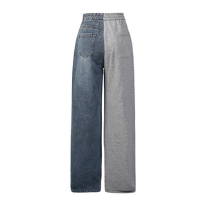 Detail view of high-waisted straight trousers with blue denim and grey jersey patchwork