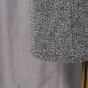 Close-up detail of grey salt and pepper wool tweed texture on a stylish overcoat