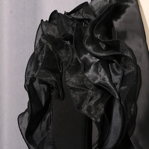 Detailed close-up of ruffle design on black satin blazer with translucent mesh trim