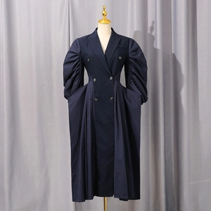 Detail of dark blue trench coat dress featuring puff sleeves and double-breasted buttons