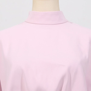 Gros plan du col montant rose clair et détail du tissu texturé sur le haut de style français