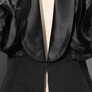 Close-up of 3D floral ruffles on shoulder of black satin lapel blazer jacket