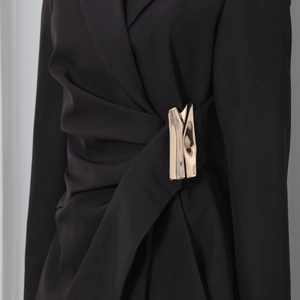 Detail of black blazer dress featuring elegant pleated waist and gold metallic button buckle