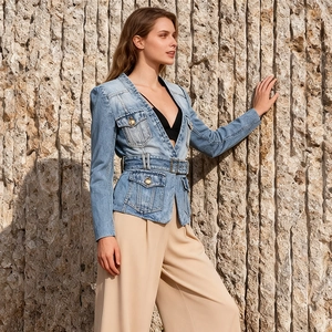 Detail of blue denim jacket with gold embossed metal buttons and waist belt design