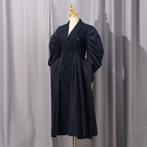 Detailed view of dark blue blazer dress featuring dramatic puff sleeves and pleated hem