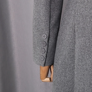 Detail of gray wool coat sleeve featuring four matte buttons on textured fabric