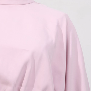 Détail du col montant élégant et du tissu texturé sur cette blouse rose clair