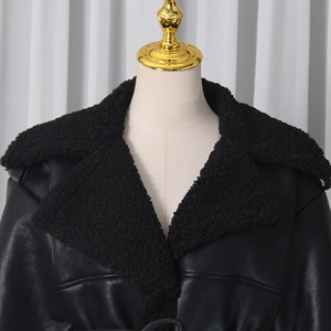 Detail of the black leather trench coat featuring a plush faux fur collar and lapel