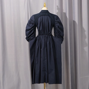 Detail of a navy windbreaker featuring unique puffy sleeves and a hollow back cutout design