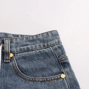 Detail of vintage blue denim with orange stitching and engraved gold rivets