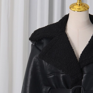 Detail of black leather coat featuring a plush faux fur collar and matching waist belt
