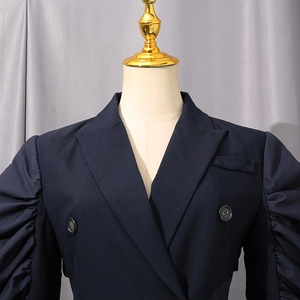 Detail view of navy blue trench coat with puff sleeves and elegant lapel on a mannequin