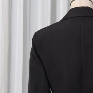Detail view of back shoulder seams and structured collar on a black tailored blazer