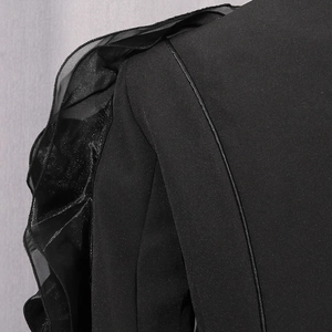Detailed view of ruffled organza shoulder detail on a sleek black blazer jacket