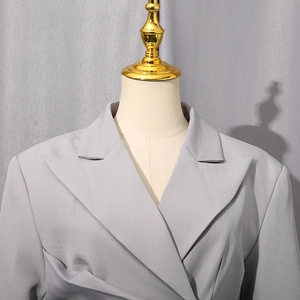 Detail eines grauen Blazers mit steigendem Revers und glatter Stoffstruktur für Damen