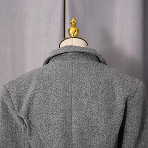 Close-up of the back and shoulder seams of a grey wool coat with thick tweed texture