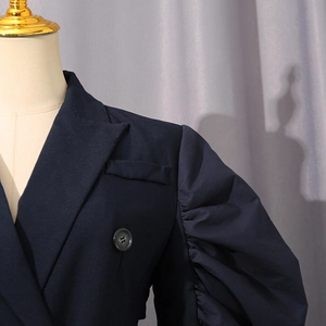 Detailed view of dark blue blazer featuring ruffle puff sleeves and classic notch lapels