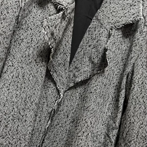 Macro shot of grey herringbone coat fabric detail with fringe trim on lapel
