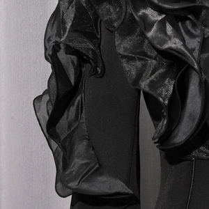 Detail of elegant black blazer featuring multi-layered satin ruffle sleeve design
