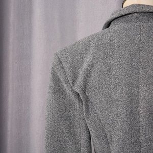 Close-up of dark grey wool coat showing neat shoulder stitching and textured fabric