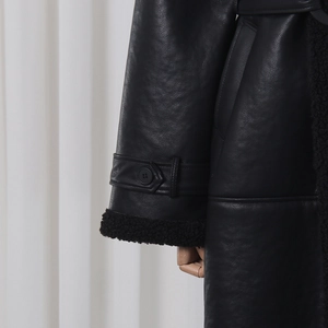 Detail of black leather coat cuff with faux fur trim and decorative strap buckle