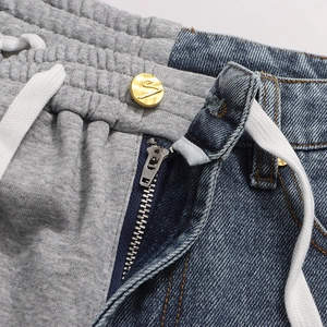 Detail of waist area showing gray jersey and blue denim patchwork with metal button
