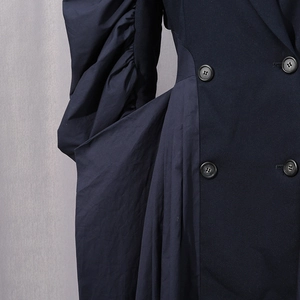 Detail of elegant navy long coat featuring ruffled puff sleeves and side drape pleats