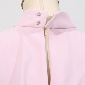 Détail du col montant rose avec doubles boutons-pression argentés et tissu texturé