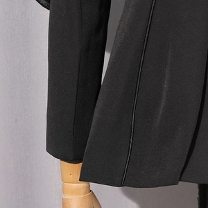 Detail view of premium black suit jacket showing fine piping and satin finish texture