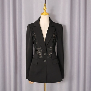 Detailed close-up of intricate lace embroidery on the waist of a black fitted blazer