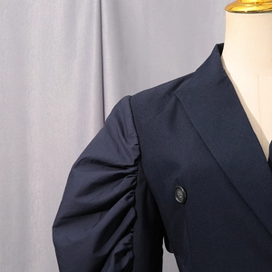 Detailed close-up of navy puff sleeve blazer with fine texture and pleated shoulder