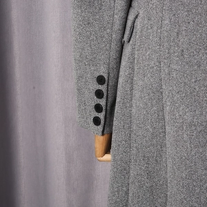 Detail shot of grey wool blend coat sleeve showing four black buttons and tweed texture