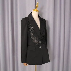Detailed close-up of intricate black lace floral embroidery on women's blazer lapel
