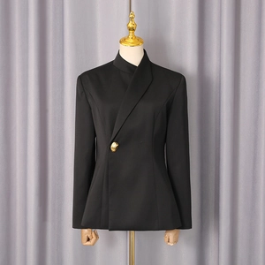 Detail of cross-wrap neckline and gold irregular button on black fitted blazer