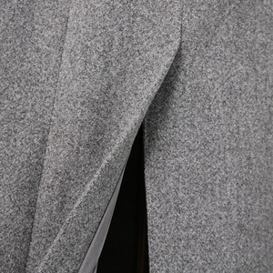 Detail view of the slit hem and smooth gray lining on a loose woolen coat