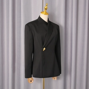 Detailed view of women black suit jacket featuring asymmetric lapel and unique gold button