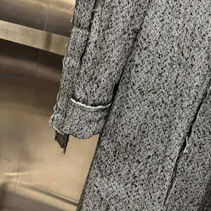Detailed view of french vintage tweed coat featuring raw-edge cuffs and woven texture