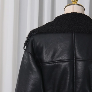 Detailed view of black faux leather jacket with plush shearling collar and stitching