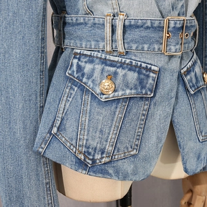 Detail of blue denim jacket with gold lion-head buttons and matching waist belt