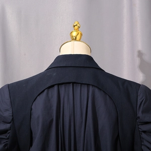 Detail view of structured navy trench coat featuring a creative open back cutout design