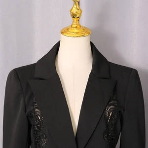 Detail of black blazer featuring intricate lace cut-out embroidery on the chest