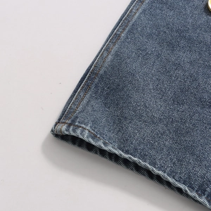 Close-up of contrast stitching on blue denim jeans with a gold metallic button detail