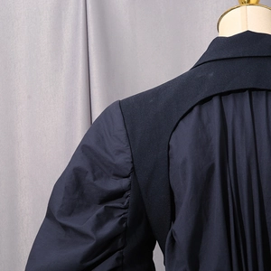 Detail of deconstructed shoulder and ruffled bubble sleeve on long navy trench coat