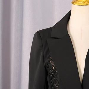 Close-up of black blazer with intricate floral lace stitching on the lapel area