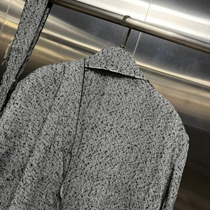 Close-up of grey herringbone wool blend fabric texture with detailed shawl collar design