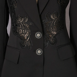Close-up of black blazer featuring intricate lace cut-out embroidery and vintage buttons