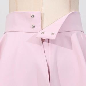 Détail de la jupe rose avec boutons métalliques, taille haute et fermeture éclair invisible